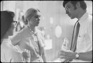 a photograph from the 1960s of a young doctor (on the right) consulting with a nursing student (left background) and nun (left foreground) in a hospital