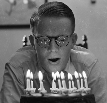 Boy blowing out birthday candles, circa 1940
