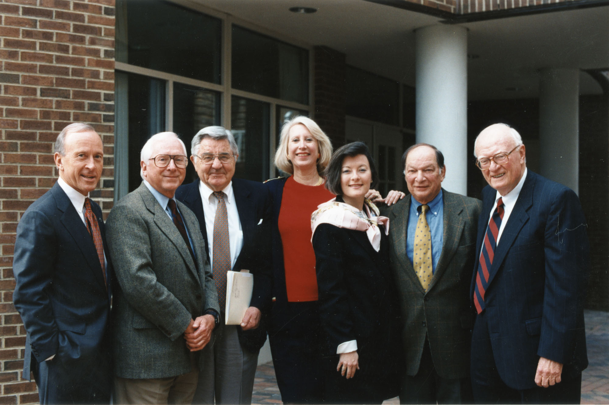 Group portrait of Cape Hatteras Lighthouse committee members, possibly outside the Carolina Club on the UNC campus. Left to right: Jim Heavner (CEO, The Village Companies of Chapel Hill and broadcaster); James G. (Jim) Babb (Executive VP, Jefferson Pilot Communications); Dr. William Friday (UNC President); unknown; unknown; Julian Scheer; and Hugh Morton.