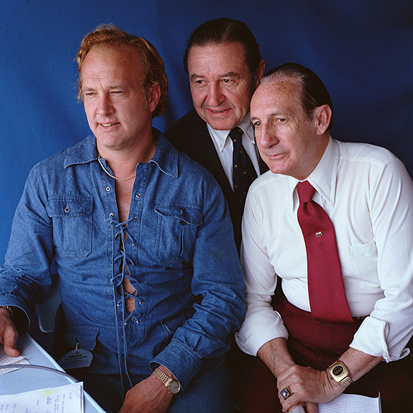 Football commentator and former quarterback Paul Hornung (left) and sportscaster Lindsey Nelson (right), while doing play-by-play for a UNC-Chapel Hill vs. Notre Dame football game. Sports broadcast producer Castleman D. Chesley at center. The year 1975 appears to be printed on Hornung's employee tag. Notre Dame scored 21 points in the fourth quarter to defeat the Tar Heels 21-14 at Kenan Memorial Stadium on October 11, 1975.