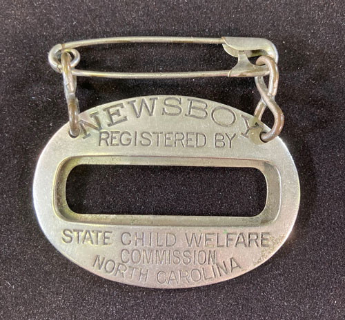 Metal oblong item with the words "Newsboy, Registered by State Child Welfare Commission, North Carolina."
