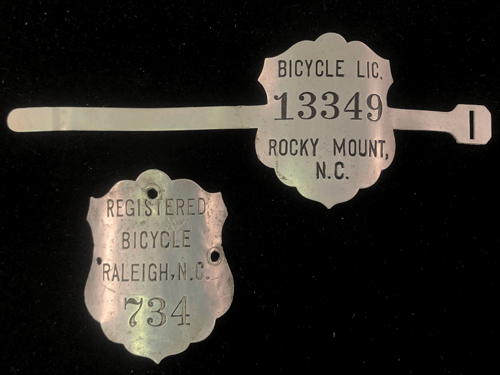 Metal shaped like badges with the names of Rocky Mount and Raleigh and numbers.