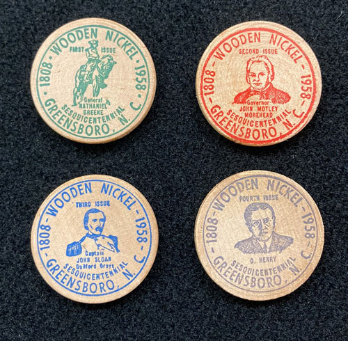 Four wooden nickels with images of John Motley Morehead, O'Henry, General Nathaniel Greene, and Captain John Sloan.