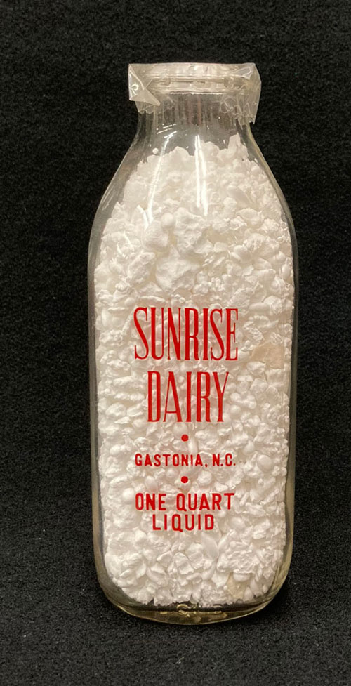 One-quart milk bottle with the words Sunrise Dairy, Gastonia, N.C. in red letters.