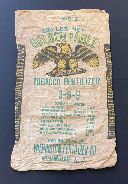 Burlap bag for tobacco fertilizer featuring the words "Golden Eagle Tobacco Fertilizer," an image of an eagle, and a list of the fertilizer ingredients.