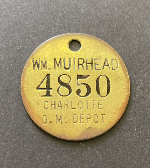 Brass tool tag with the words "William Muirhead and Charlotte Q.M. Depot."