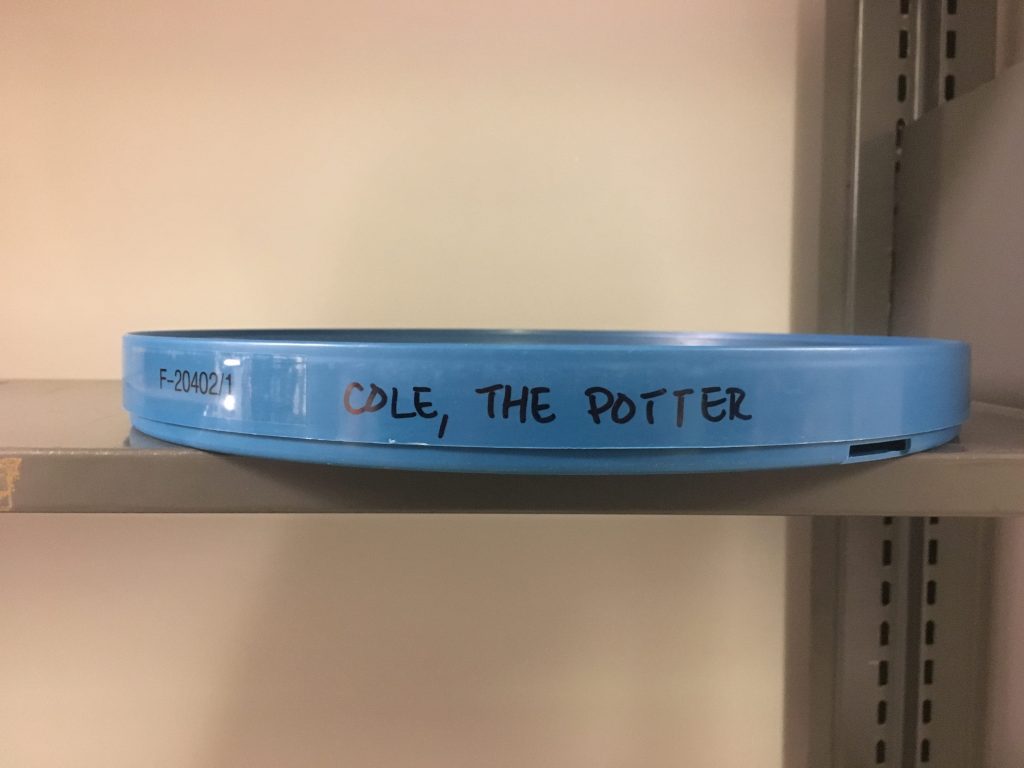 Side view of blue, plastic film can for 16mm film, call number F-20402_1, with "Cole, the Potter" written in black marker