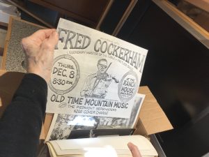 Diane Alden pointing out a flyer for Fred Cockerham performance at the Ranch House Back Room in Chapel Hill, NC