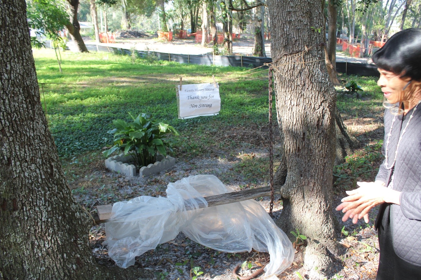 Mrs. Franklin points out a simple wooden board suspended between two trees, covered in plastic wrap and marked with a sign reading, "Thank you for Not Sitting."