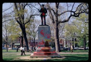 Red and yellow graffiti sprayed on the base of "Silent Sam."