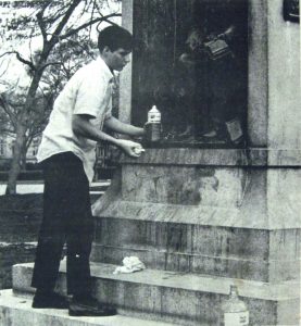A student volunteer cleans graffiti from the base of "Silent Sam,"  April 8, 1968. From the Daily Tar Heel,  April 9, 1968, North Carolina Collection, Wilson Library, UNC Chapel Hill.