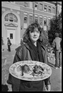 Student holding a platter containing items symbolizing CIA-led violence